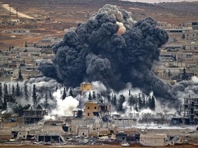 FILE - In this Monday, Nov. 17, 2014 file photo, smoke rises from the Syrian city of Kobani, following an airstrike by the U.S.-led coalition, seen from a hilltop outside Suruc, on the Turkey-Syria border. Syrian activists and Kurdish officials say the extremist Islamic State group has been nearly pushed out of the Syrian border town of Kobani.