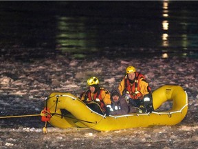 Firefighters rescue one of three people after they were stranded in a canoe on the Ottawa River behind Parliament Hill in Ottawa, Thursday, January 1, 2015.