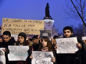 A man holds a placard reading: "Freedom of the press is priceless, fundamentalism, of any kind, will not pass" as others hold up placards reading in French, "I am Charlie" during a gathering at the Place de la Republique (Republic square) in Paris, on January 7, 2015, following an attack by unknown gunmen on the offices of the satirical weekly, Charlie Hebdo. France's Muslim leadership sharply condemned the shooting at the Paris satirical weekly that left at least 12 people dead as a "barbaric" attack and an assault on press freedom and democracy.