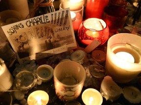 A postcard reading "Let's be Charlie" is placed next to candles during a rally at Republic Square in Paris on January 8, 2015, a day after a deadly attack on the headquarters of French satirical magazine Charlie Hebdo. Elite French security forces tightened the net on two brothers suspected of slaughtering 12 people in an Islamist attack after discovering an abandoned getaway car in a northeastern town.