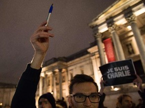 People holds pens and posters in the air as they gather in Trafalgar Square in central London to show their respect for the twelve people killed in Paris today in a terrorist attack at the headquarters of satirical publication "Charlie Hebdo" on January 7, 2015.