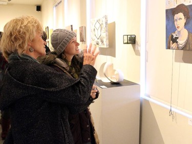 From left, Val Roy and Amanda Cox study a painting done by Chelsea artist Reid McLachlan at the vernissage for Cube Gallery's 10th anniversary exhibition, held Sunday, January 11, 2015.