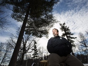 Graham Saul, executive director of Ecology Ottawa, sits on the stump of a felled ash tree in Hampton Park.