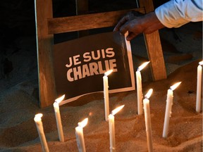 Candles are lit next to a sign reading "Je suis Charlie" (I am Charlie) in Abidjan on January 9, 2015 during a gathering held by the foreign press association in Ivory Coast to pay tribute to the victims of a deadly attack on the Paris headquarters of French satirical weekly Charlie Hebdo.