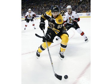Boston Bruins' Brad Marchand (63) controls the puck in front of Ottawa Senators' Kyle Turris (7) during the first period of an NHL hockey game in Boston, Saturday, Jan. 3, 2015.