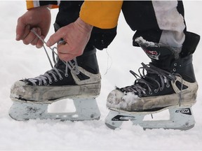 LAKE LOUISE, CANADA - MARCH 2: A player ties his skate laces during outdoor shinny hockey action at the 4th Annual Lake Louise Pond Hockey Classic on the frozen surface of Lake Louise on March 2, 2013 in Lake Louise, Alberta, Canada.