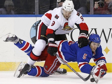 Ottawa Senators left wing Milan Michalek (9), of the Czech Republic, trips over New York Rangers defenseman Dan Girardi (5) as both try to get to a loose puck during the first period.