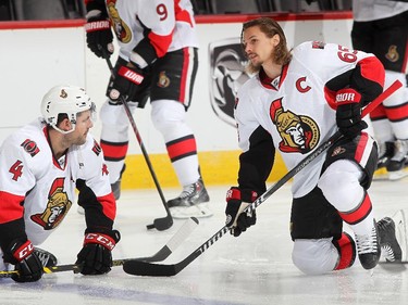 Chris Phillips #4 and Erik Karlsson #65 of the Ottawa Senators stretch prior to the game against the Colorado Avalanche.