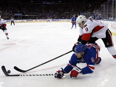 Dan Girardi #5 of the New York Rangers slides for the puck against Milan Michalek #9 of the Ottawa Senators.