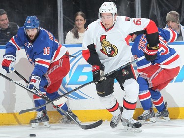 Mark Stone #61 of the Ottawa Senators skates with the puck against Derick Brassard #16 and Mats Zuccarello #36.