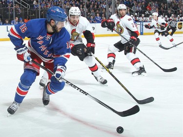 Derick Brassard #16 of the New York Rangers skates with the puck against Cody Ceci #5 and Jared Cowen #2 of the Ottawa Senators.