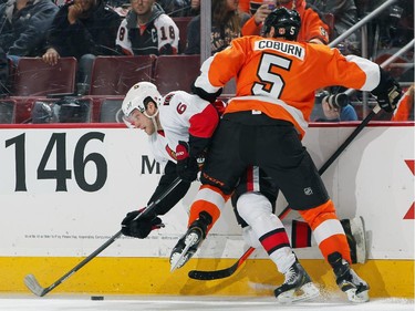 Braydon Coburn #5 of the Philadelphia Flyers checks Bobby Ryan #6 of the Ottawa Senators into the boards as they pursue the loose puck.