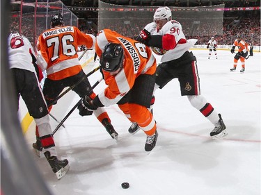 Nicklas Grossmann #8 of the Philadelphia Flyers is checked to the ice by Alex Chiasson #90 of the Ottawa Senators as they battle for the loose puck in the corner.