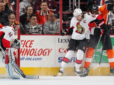 Craig Anderson #41 of the Ottawa Senators looks on as Erik Karlsson #65 battles for the loose puck with Wayne Simmonds #17 of the Philadelphia Flyers.