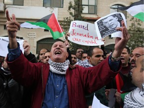 Palestinian protesters wave national flags shouting slogans outside the Foreign Affairs ministry where Palestinian Minister of Foreign Affairs Riyad al-Maliki meets his Canadian counterpart John Baird on January 18, 2015 in the West Bank city of Ramallah. Angry Palestinian youths hurled eggs at the motorcade of Baird as he was leaving after the meeting.