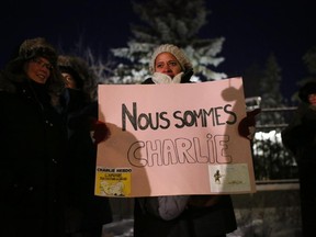 People hold signs and show their support at a vigil at the French Embassy in Ottawa, for the slain journalists of the Paris satirical magazine Charlie Hebdo who were murdered this morning at their offices in Paris.