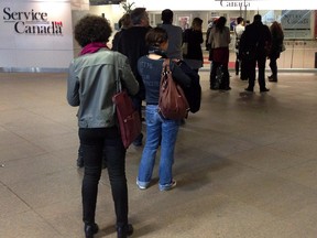 People wait for the Service Canada employment centre to open on April 2, 2014 in Montreal. Statistics Canada said 11,000 net jobs were lost between July and August of this year.