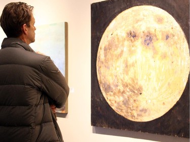 Rory Magill examines an acrylic on wood piece by Don Monet at the vernissage for Cube Gallery's 10th anniversary exhibit, held Sunday, January 11, 2015.