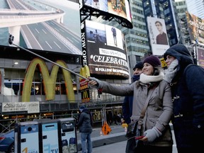 Excited visitors to New York City take selfies in front of one of Times Square's many fine restaurants. (AP Photo)
