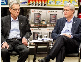 Canadian Prime Minister Stephen Harper (right) sits with Joe Oliver, Minister of Finance, as they participate in a roundtable discussion at a Canadian Tire Store in Mississauga, Ont., on Thursday, December 11, 2014.