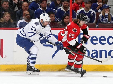 Erik Karlsson #65 of the Ottawa Senators skates with the puck ahead of Trevor Smith #23 of the Toronto Maple Leafs.