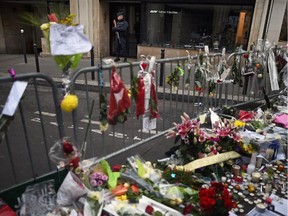 Members of the public view flowers and tributes left near the offices of French satirical magazine Charlie Hebdo on January 10, 2015 in Paris, France.