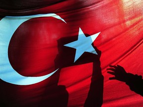 A supporter of Zaman holds a copy of the newspaper behind a Turkish flag during a demostration against the arrest of journalists outside the Istanbul police headquarters on December 15, 2014.