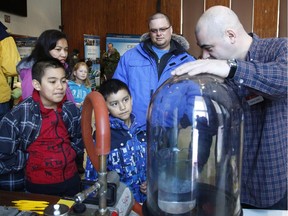 Alex Gordon, left, age 10, Jacob Gordon, age 7, Antoineta Gordon, mom, and Ben Gordon, dad, look at water boiling inside a vacuum while University of Ottawa physicist Christian Gigault, right, explains the exhibit at a Cool SCience Event at Natural Resources Canada on Booth Street in Ottawa on Sunday, February 15, 2015.