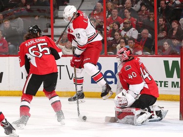 Eric Staal #12 of the Carolina Hurricanes jumps to avoid getting hit by the puck as Erik Karlsson #65 and Robin Lehner #40 defend their net.