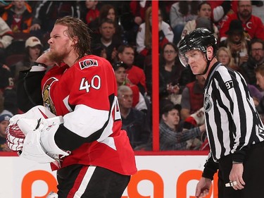 Robin Lehner #40 of the Ottawa Senators grimaces as he leaves the ice after being injured at the end of the second period against the Carolina Hurricanes as linesman Jean Morin looks on.