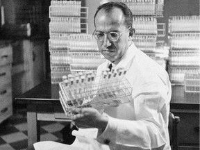 In this Oct. 7, 1954 file photo, Dr. Jonas Salk, developer of the polio vaccine, holds a rack of test tubes in his lab in Pittsburgh, Pa.