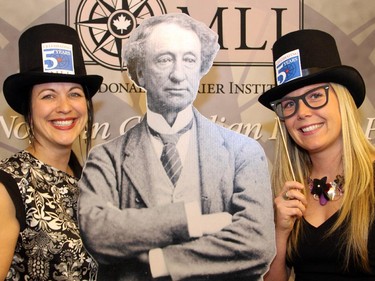 From left, Canadian Museum of History employees Geneviève Mercier and Tracy Campbell posed with props alongside a cutout of Sir John A. Macdonald at a special Macdonald-Laurier Institute dinner held at the museum on Wednesday, February 18, 2015, in honour of 200th birthdate of Canada's first prime minister.