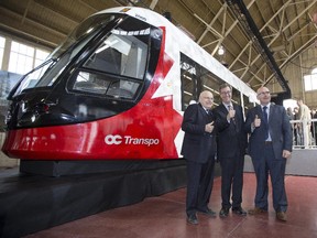 From left, MP Royal Galipeau, Mayor Jim Watson and Ontario Transportation Minister, Steven Del Duca, pose for a photo during an unveiling of the future of transit in Ottawa - a full-sized mock-up of the Alstom Citadis Spirit light rail vehicle that will be used on the O-Train Confederation Line, the backbone of Ottawa's new light rail transit system Thursday January 29, 2015.
