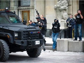 Ottawa Police and RCMP remove Chief of Defence staff, Tom Lawson, from an exit behind the Canada Post building on Sparks street Wednesday October 22, 2014.