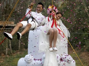 Groom, Chaiyut Phuamgphoeksuk, left and bride, Prontathorn Pronnapatthun right jump from a 3.5 meter high wedding cake, as a part of an adventure-themed wedding ceremony in Ratchaburi Province, Thailand, Friday, Feb. 13, 2015, on the eve of Valentine's Day.