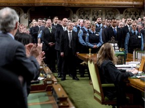 House of Commons security personnel receive a standing ovation from Members of Parliament as they are honoured in the House of Commons for their efforts during the October shooting on Parliament Hill, Thursday December 11, 2014 in Ottawa.