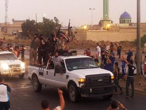 In this photo taken Wednesday, June 25, 2014, fighters of the al-Qaida-inspired Islamic State of Iraq and the Levant (ISIL) parade in the northern city of Mosul, Iraq. Two weeks has passed since the Islamic State of Iraq and the Levant took over the country's second largest city. U.S. Secretary of State John Kerry warned Mideast nations on Wednesday against taking new military action in Iraq that might heighten already-tense sectarian divisions, as reports surfaced that Syria launched airstrikes across the border and Iran has been flying surveillance drones over the neighboring country.