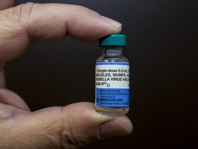 In this Thursday, Jan. 29, 2015 photo, pediatrician Charles Goodman holds a dose of the measles-mumps-rubella, or MMR, vaccine at his practice in Northridge, Calif.