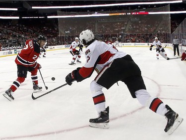 New Jersey Devils defenseman Marek Zidlicky, left, of the Czech Republic, clears the puck away as Ottawa Senators defenseman Jared Cowen, center, attacks during the first period.