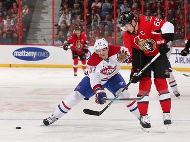 Erik Karlsson #65 of the Ottawa Senators passes the puck against the tight fore-checking of Max Pacioretty #67 of the Montreal Canadiens.