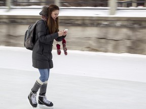 Nadine Gannam checks out her smartphone while skating on the Rideau Canal.