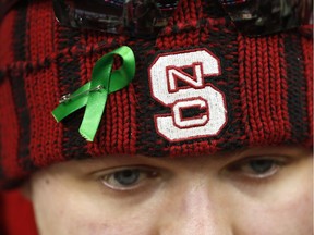 NC State sophomore Drew Blevins wears a green ribbon before an NCAA college basketball game between Virginia and NC State, Wednesday, Feb. 11, 2015, in Raleigh, N.C. Student body president Rusty Mau said that the ribbons are, "To remember the lives lost in Chapel Hill."