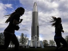 Two teenagers run by the Convair GCM-16 Atlas long-range rocket that was the launch vehicle that carried Lt.Col John Glenn of the United States Marine Corps into orbital flight around the Earth in 1962
