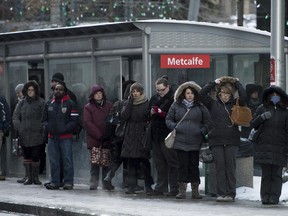 Commuters, bundled from the cold, wait for OC Transpo buses on Slater Street.