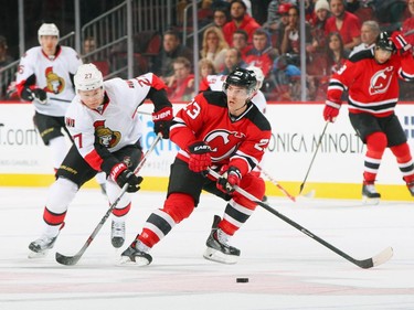 Curtis Lazar #27 of the Ottawa Senators and Mike Cammalleri #23 of the New Jersey Devils pursue a loose puck.