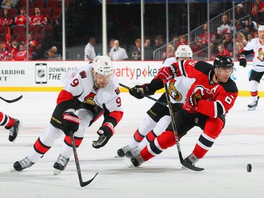 Milan Michalek #9 of the Ottawa Senators and Andy Greene #6 of the New Jersey Devils pursue a loose puck.