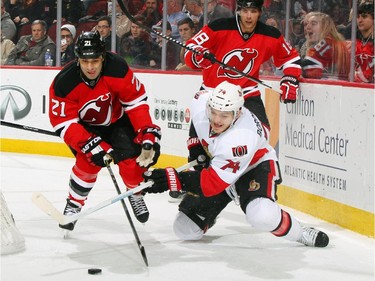 Mark Borowiecki #74 of the Ottawa Senators and Scott Gomez #21 of the New Jersey Devils battle for a loose puck.
