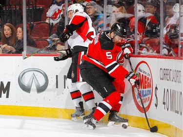 Adam Larsson #5 of the New Jersey Devils wins the puck from Erik Condra #22 of the Ottawa Senators during the first period.