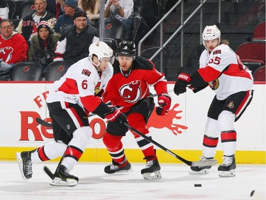 Dainius Zubrus #8 of the New Jersey Devils battles for the puck against Bobby Ryan #6 and Erik Karlsson #65 of the Ottawa Senators.