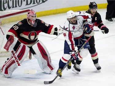 Washington Capitals left wing Alex Ovechkin battles with Ottawa Senators defenseman Erik Karlsson in front of Senators goalie Robin Lehner during second period NHL action.